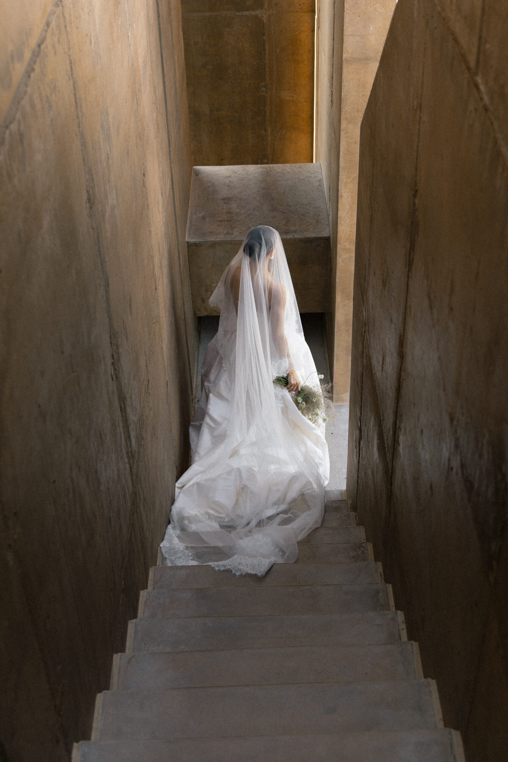 Bride in Mia Atelier gown walking down concrete stairs at Folly Mojave in Twentynine Palms California desert